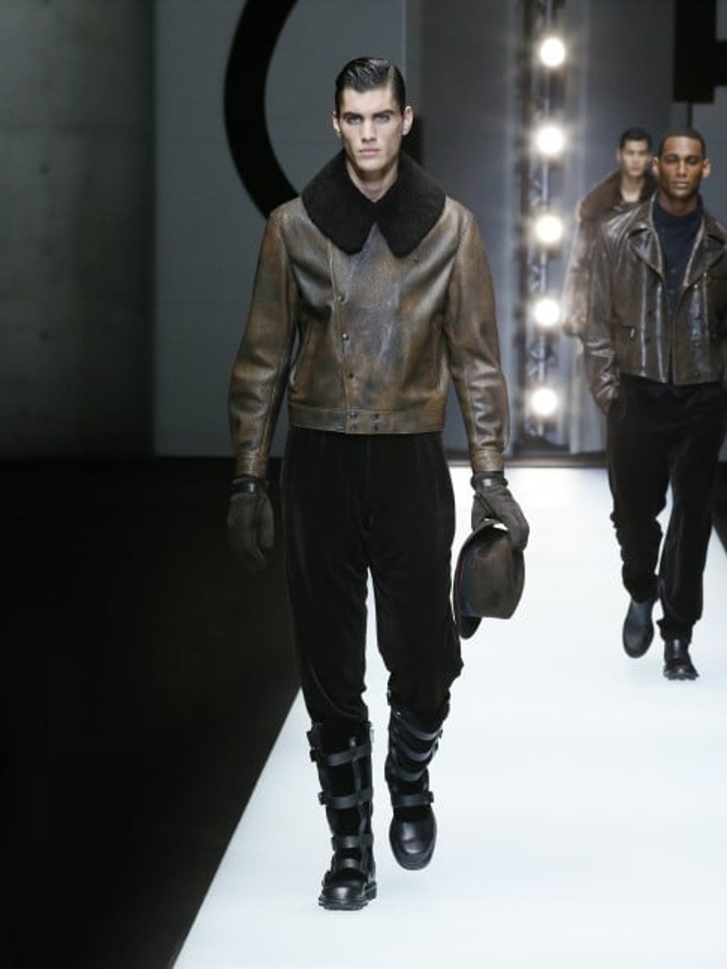 Brown buffered lambskin leather jacket with sheepskin collar, trousers in brown pinstripe flocked velvet, brown rabbit fur Fedora hat, and dark brown sheepskin gloves.