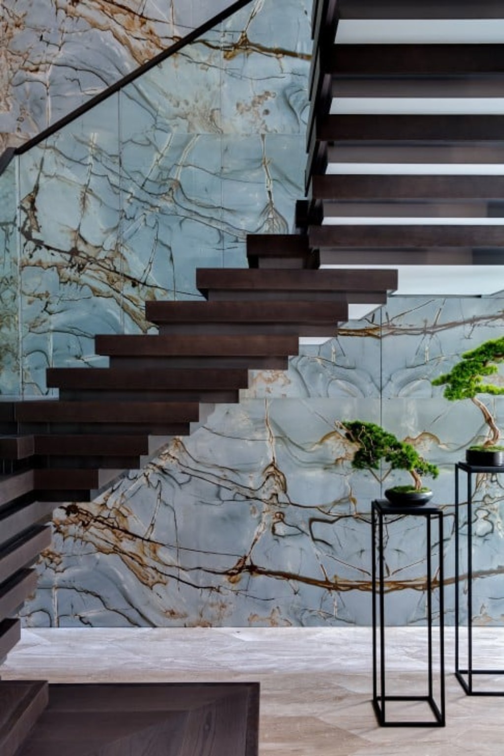 The cool blue tones of the marble wall combine with the rich wood of the staircase and delicate bonsai to evoke a natural scene in an interstitial space. (This photo was taken on February 20–21, 2021 at 23–39 Blue Pool Road. This photo has been processed by computerised imaging techniques and is for reference only.)