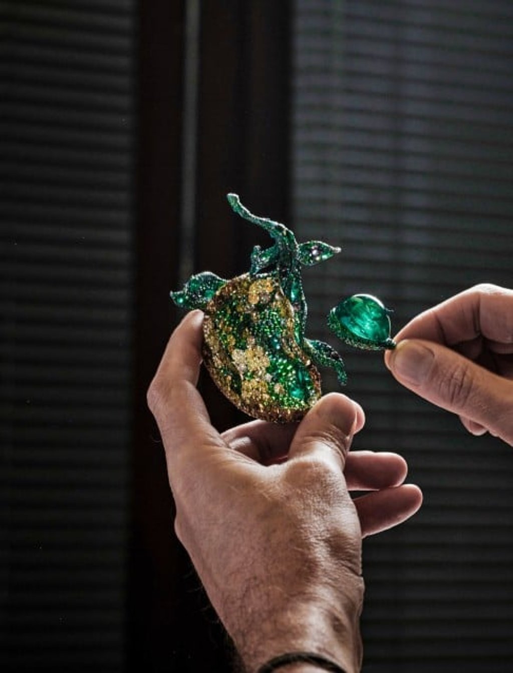 A master gem setter embeds an 81-carat oval Colombian cabochon emerald into the pod using the invisible mortise and tenon joinery technique.