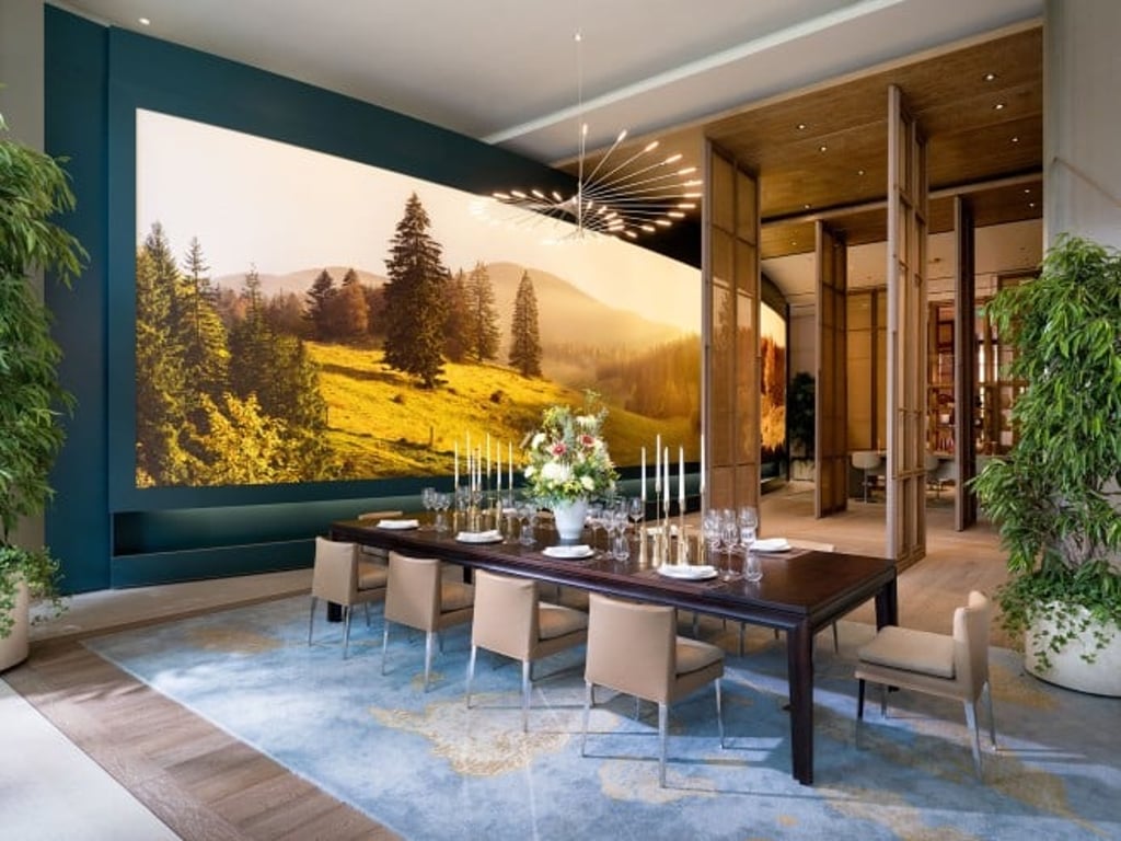 The wall-sized screen display showing the changing seasons in Le Brassus spans the dining area and beyond.