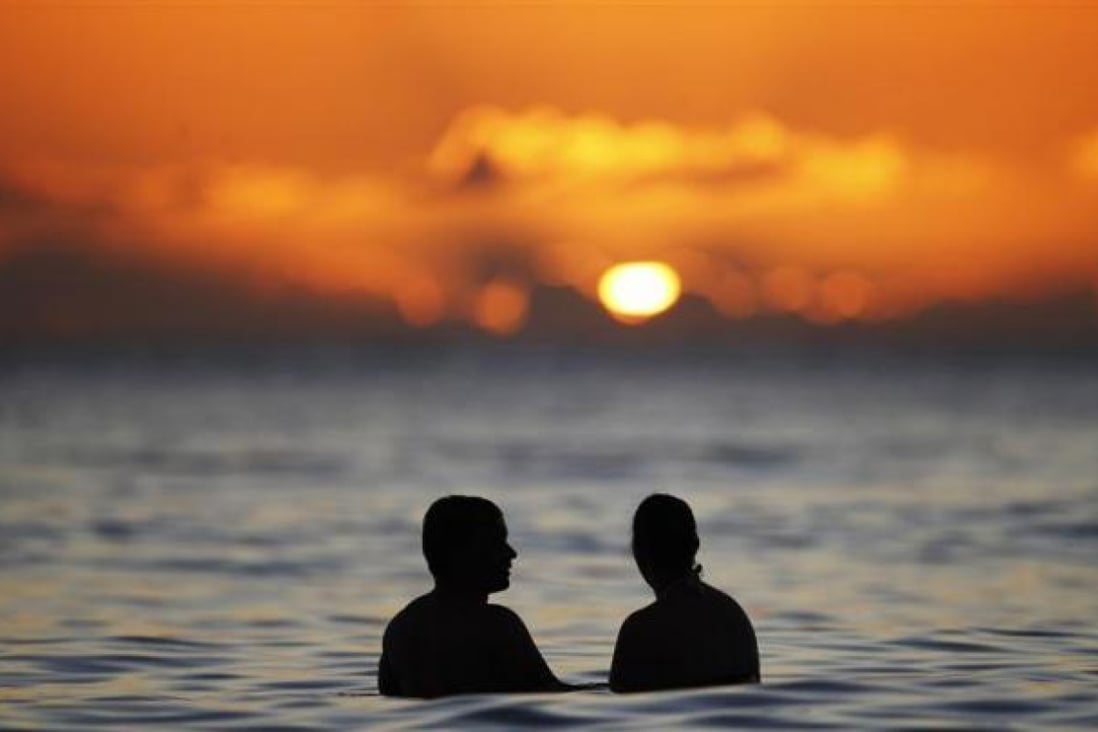A couple watches the last rays of sunlight for 2011 at sunset from the waters off Waikiki Beach in Honolulu, Hawaii, December 31, 2011. REUTERS/Jason Reed