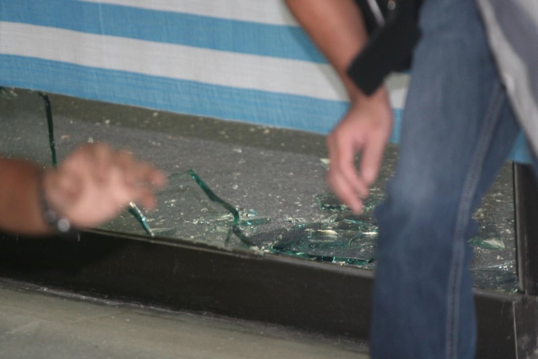 Officers collect evidence after three masked men used axes to damage the Sing Tao Centre in Mody Road. Photo: SCMP