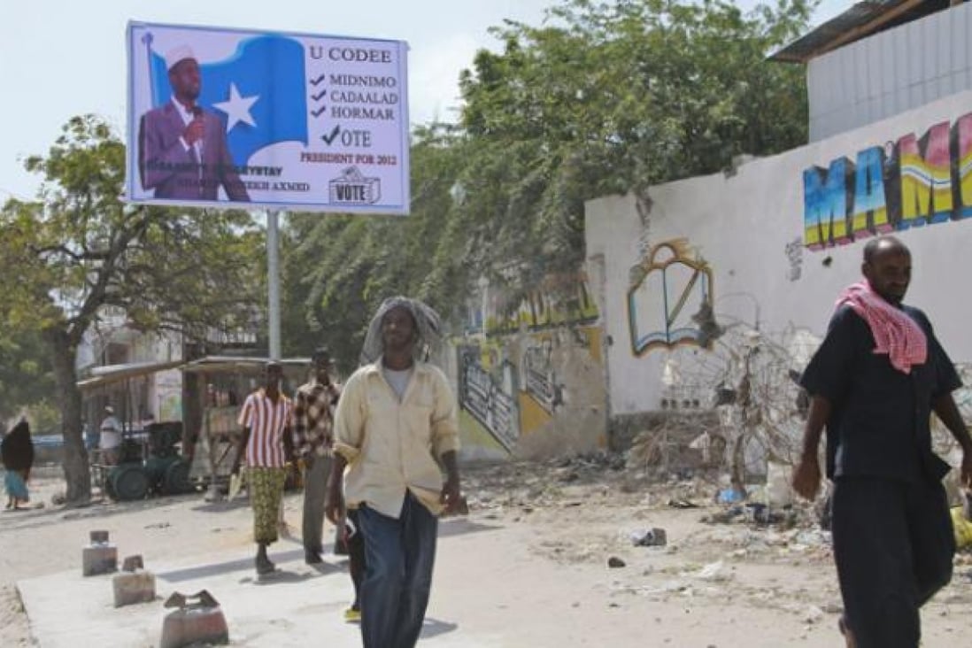 Pedestrians walk past a campaign billboard of incumbent president Sharif Sheikh Ahmed in the capital Mogadishu on Sunday. Photo: EPA