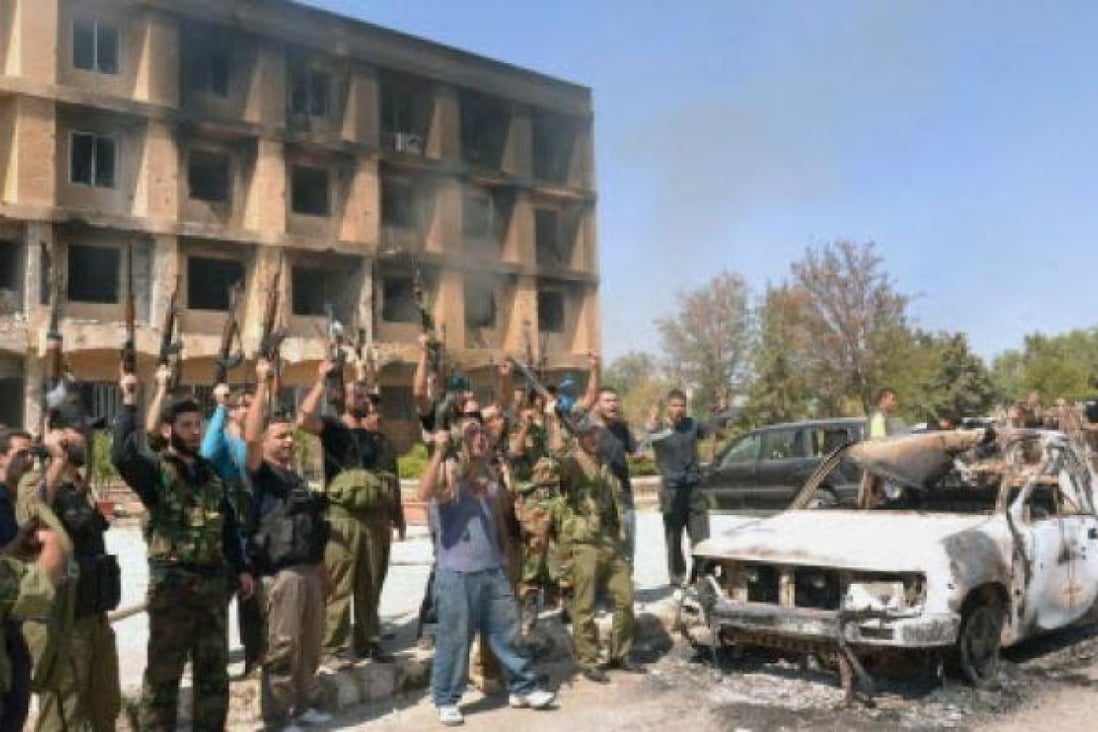 Syrian army soldiers raise their guns outside a research centre following clashes with rebels in Aleppo. At least 30 civilians were reported killed on Thursday in a massive explosion in northeast Syria.