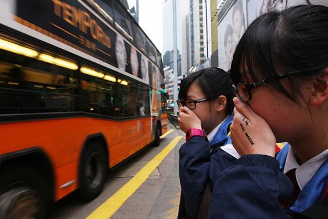 Students cover their faces to avoid traffic fumes in Causeway Bay. Photo: Nora Tam