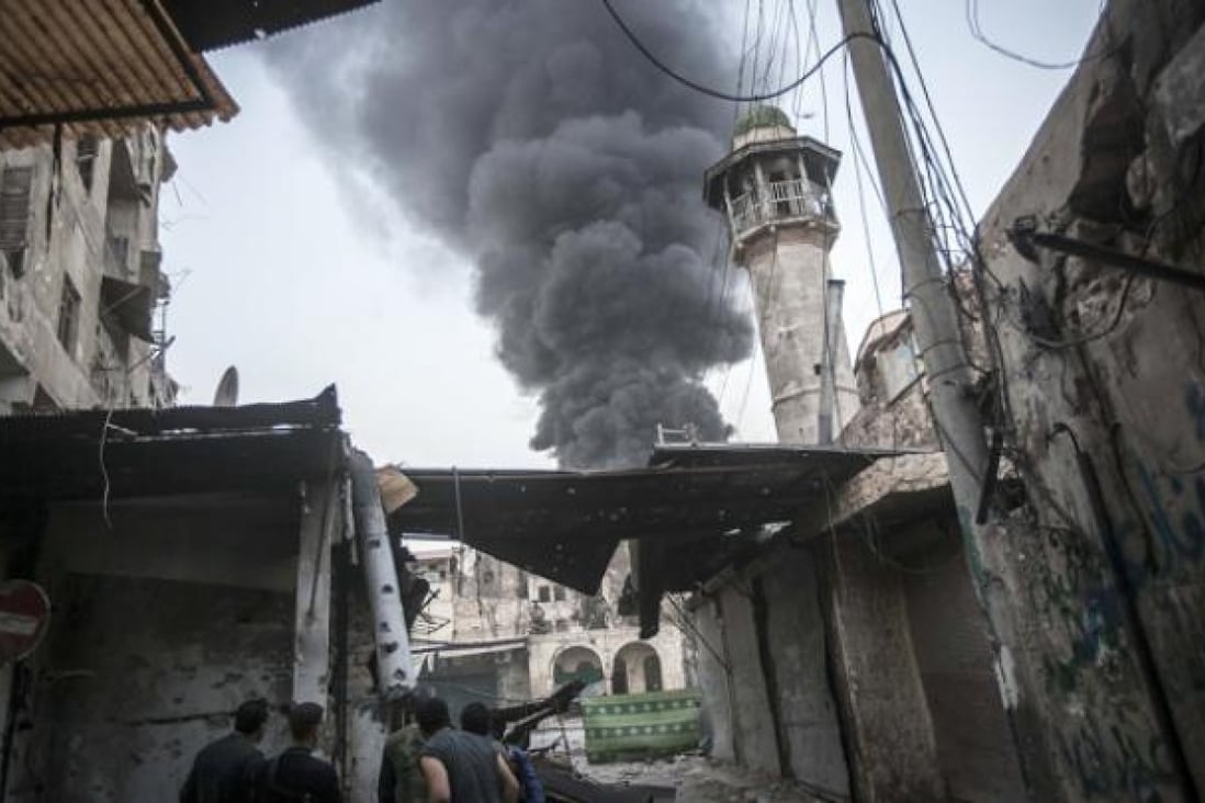 Rebel fighters watch as smoke rises after Syrian government forces fired an artillery round at a rebel position during heavy clashes in Aleppo on Sunday. Photo: AP