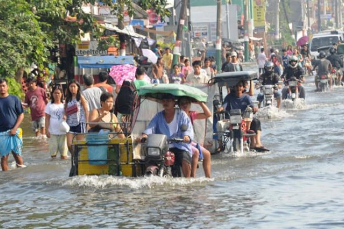 Residents commute along a flooded stretch of road in Calumpit town, north of Manila on August 11. Photo: AFP