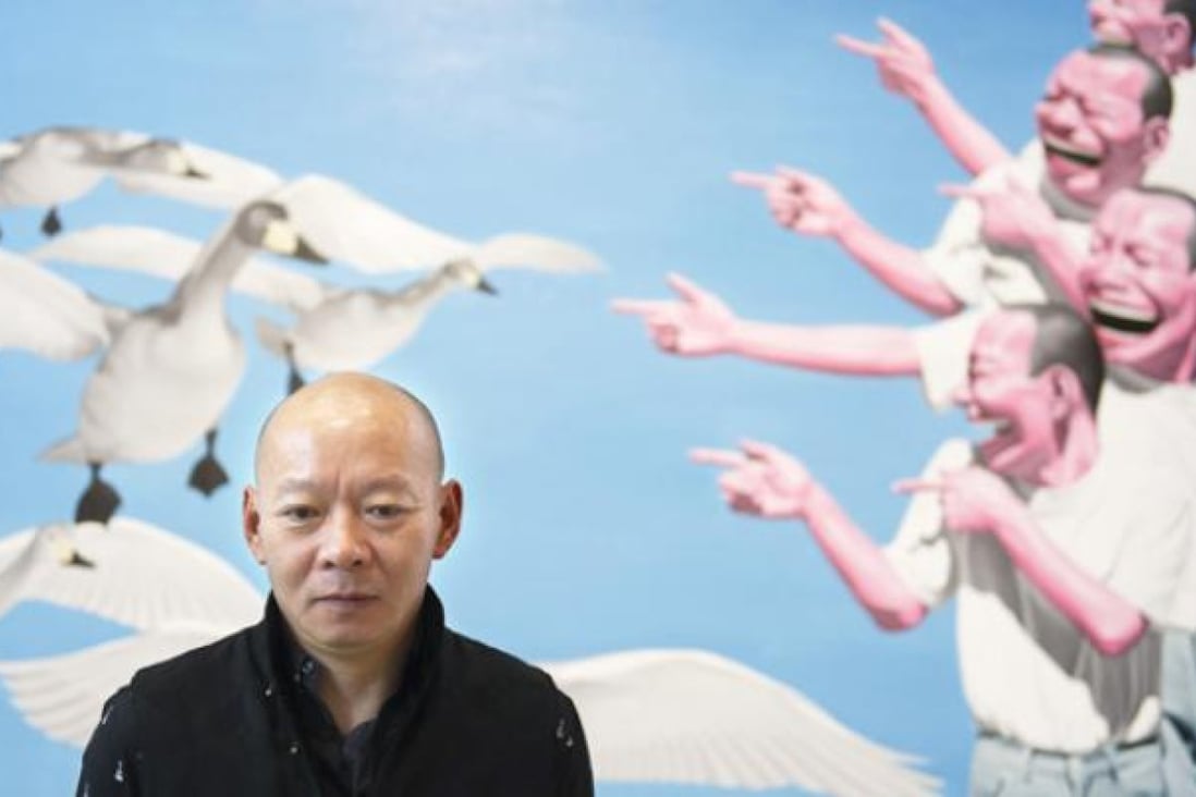 Yue Minjun poses in front of one of his paintings displayed in an exhibition entitled "L'ombre d'un fou rire" (The shadow of a laugh) in Paris on Tuesday. Photo: AFP