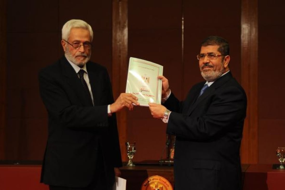 Egyptian President Mohamed Mursi (right) receives the final draft of Egypt's constitution from Hossam El-Gheriany, head of the Constituent Assembly on Saturday. Photo: Xinhua