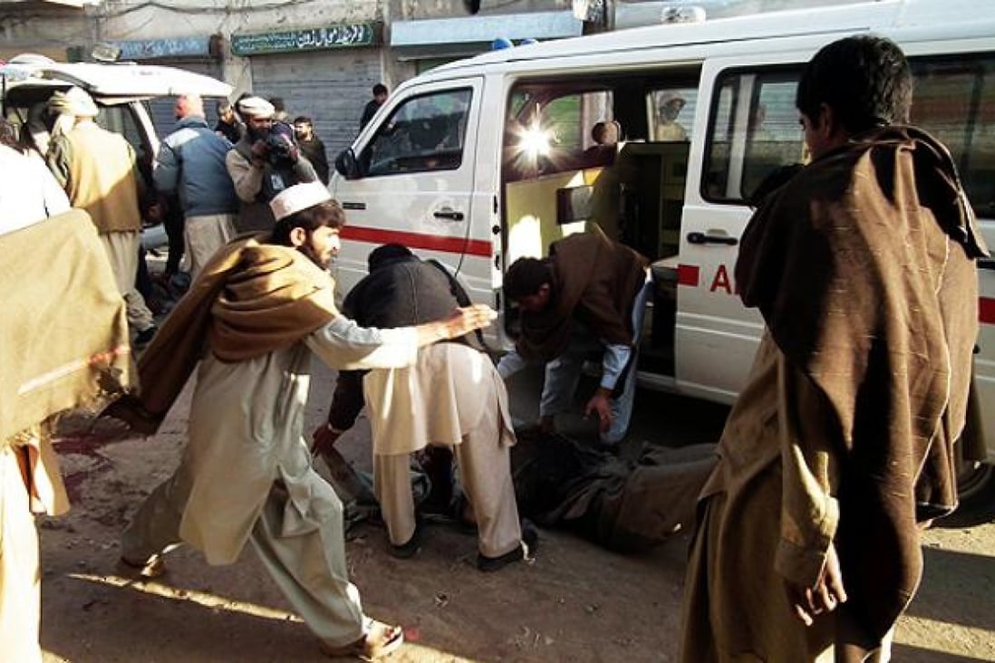 Pakistani people transfer a body from the suicide blast site in northwest Pakistan's Bannu on Monday. Photo: Xinhua