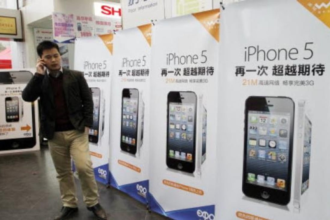  A customer stands in front of ad boards of Apple's iPhone 5 at a telecom retail store in Nanjing. Photo: Xinhua