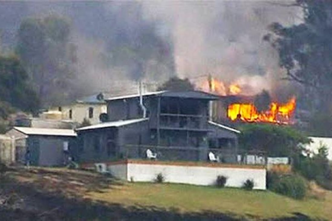 A house burns in the Tasmanian town of Dunalley on Saturday as bush fires rage in Australia. Photo: Reuters