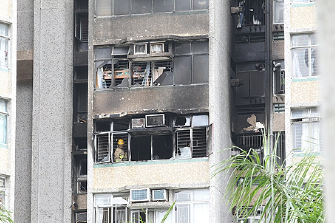 Firemen inspect the ninth-floor Cypress House flat in the Kwong Yuen housing estate in Sha Tin where a fire caused the death of a woman and injured four people early on Friday morning. Photo: Edward Wong