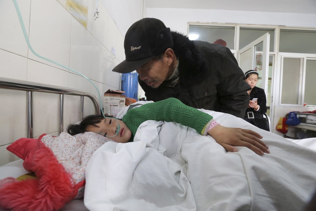 An elderly man talks to a girl who was injured after a stampede accident at a primary school, at a hospital in Xiangyang, Hubei province. Photo: Reuters