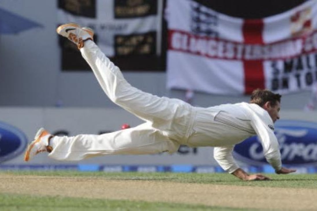 New Zealand's Bruce Martin dives to field off his own bowling against England on the second day of the 3rd international cricket test in Auckland on Saturday. Photo: AP