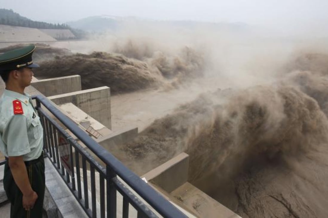 Chinese paramilitary guard watching over giant gushes of water being released from the Xiaolangdi dam. Photo: AFP