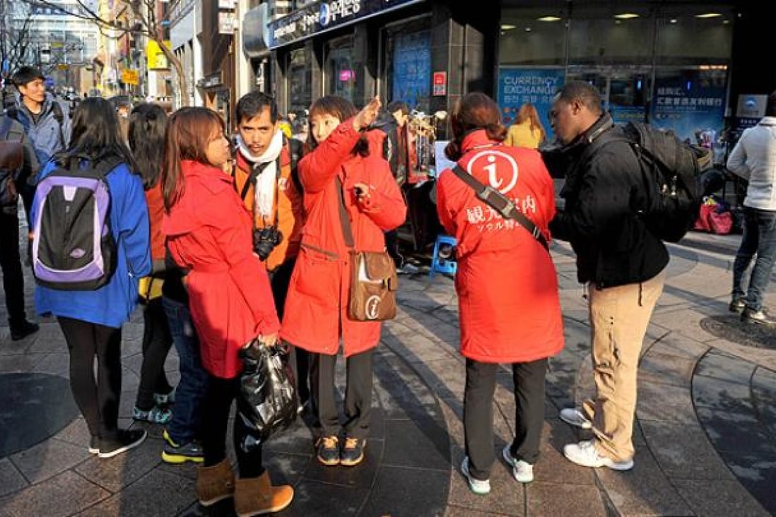 Tourists consult with tour guides in a shopping district of Seoul. Photo: AFP