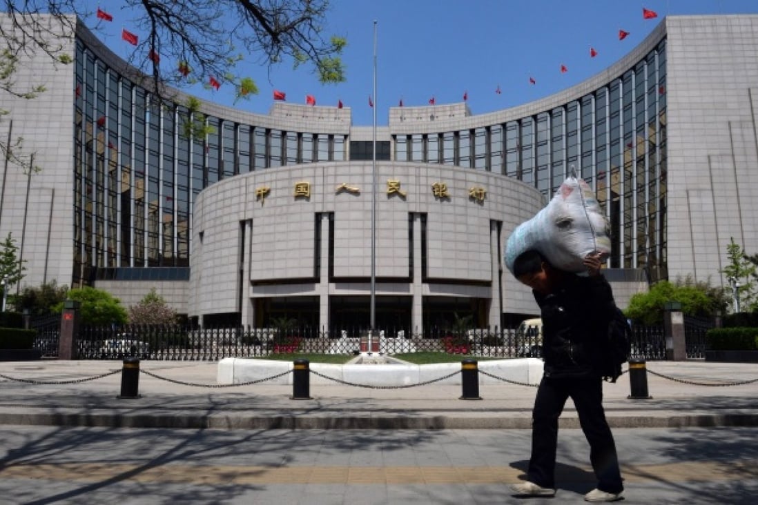A Chinese migrant worker passes by The People's Bank of China as he heads to a bus station in Beijing. Photo: AFP