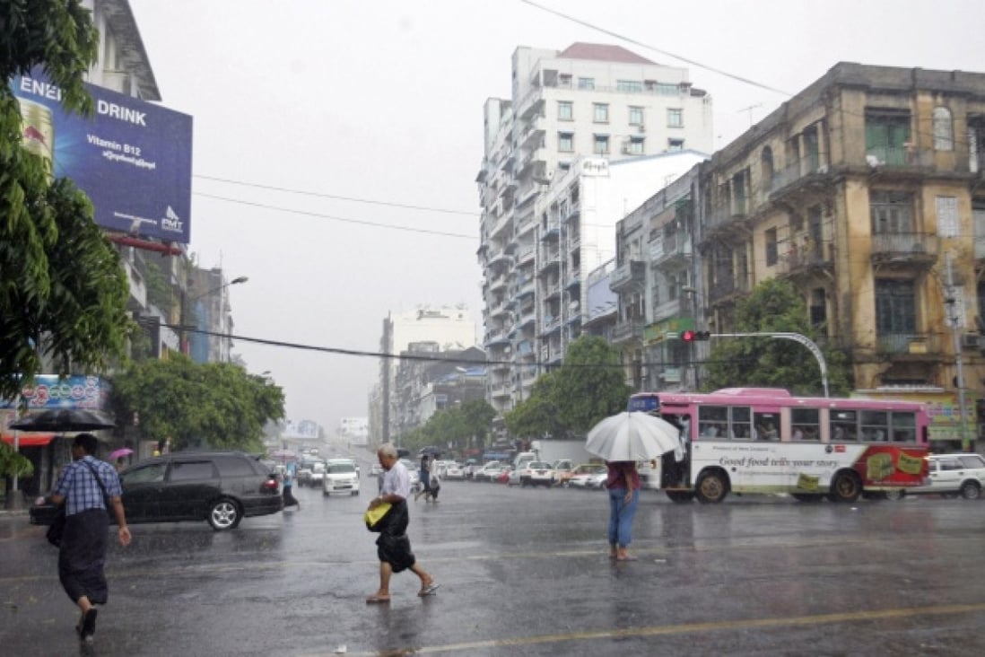 Pedestrians cross a road in the rain in Yangon, Myanmar. Photo: AP