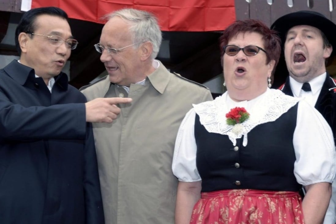 Li Keqiang comments to Swiss minister Johann Schneider-Ammann as yodellers perform. Photo: EPA