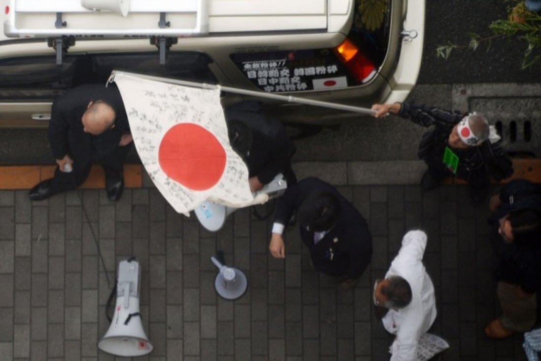 Demonstrators carrying Japanese "Rising Sun" flags stage a protest rally in front of a building where the Tokyo bureau of the Joongang Ilbo is located. Photo: AFP