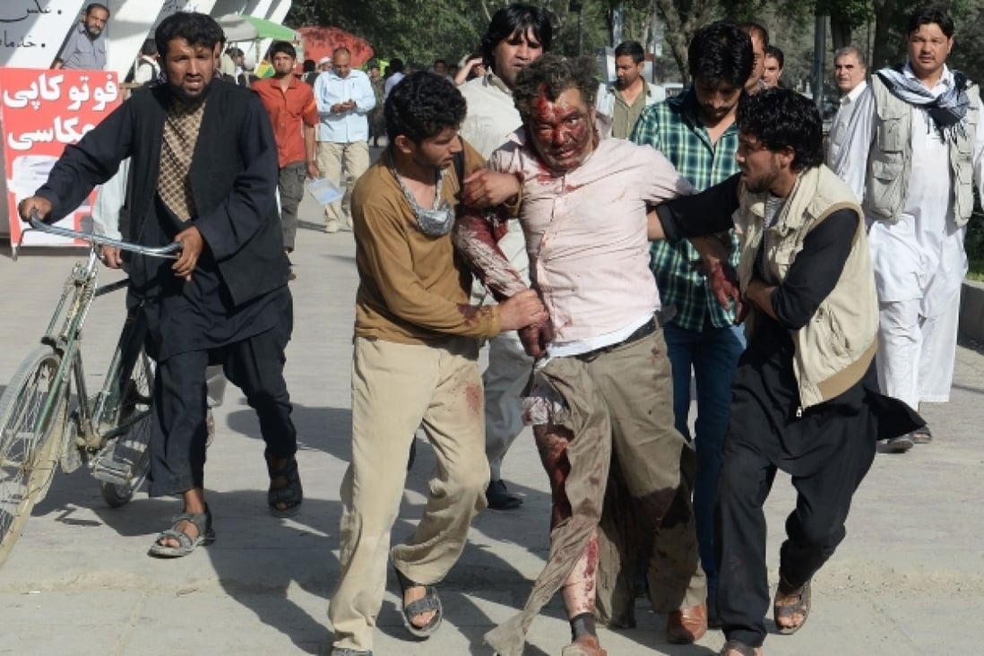 Afghan men assist an injured man at the site of a suicide attack in Kabul. Photo: AFP
