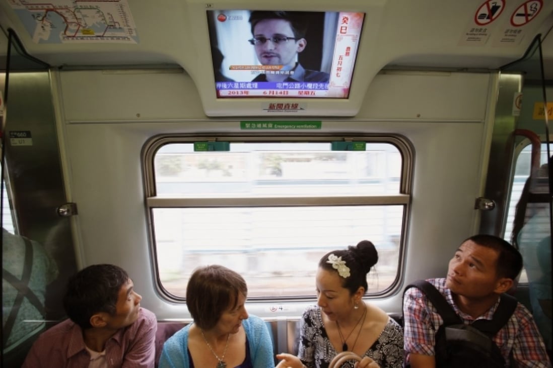 Passengers watch news of Snowden on a train in Hong Kong. Photo: Reuters