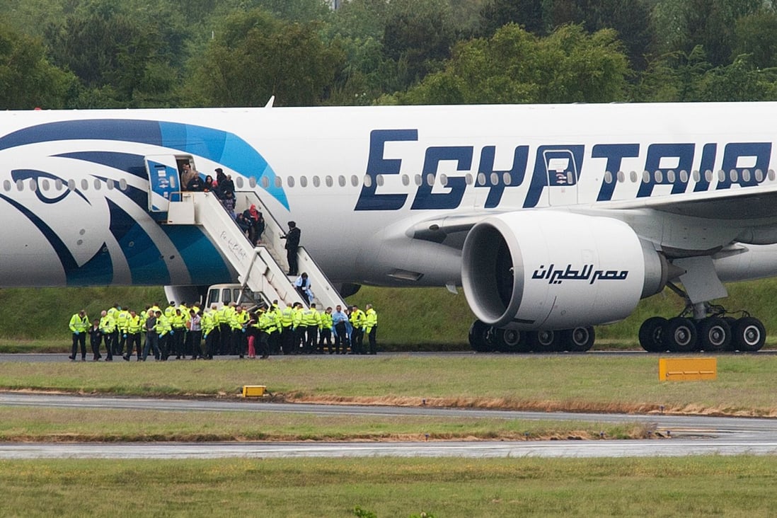 Police escort passengers off the EgyptAir Boeing 777 flight from Cairo that was forced to land at Glasgow Prestwick airport in Scotland. Photo: AFP