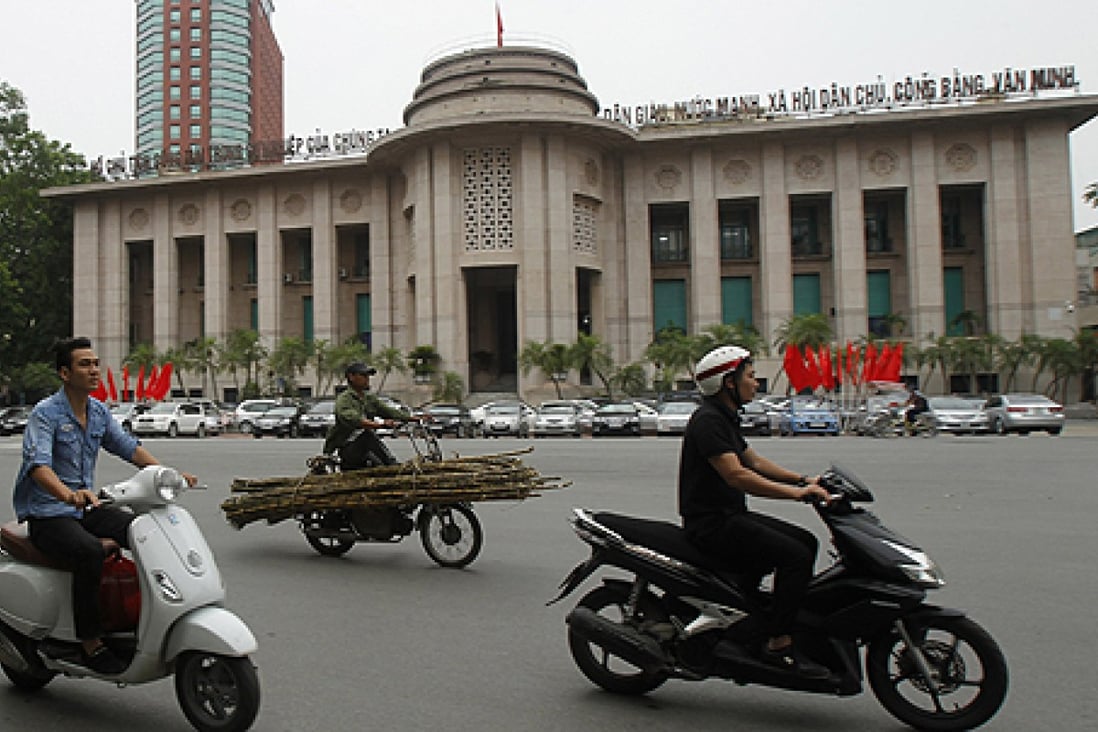 Men on motorcycles ride past the State Bank of Vietnam building in Hanoi. Photo: Reuters