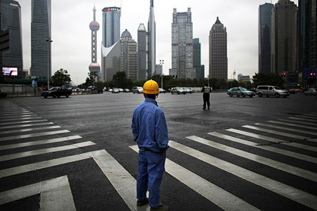 A construction worker looks at Pudong financial district in Shanghai. Photo: Reuters