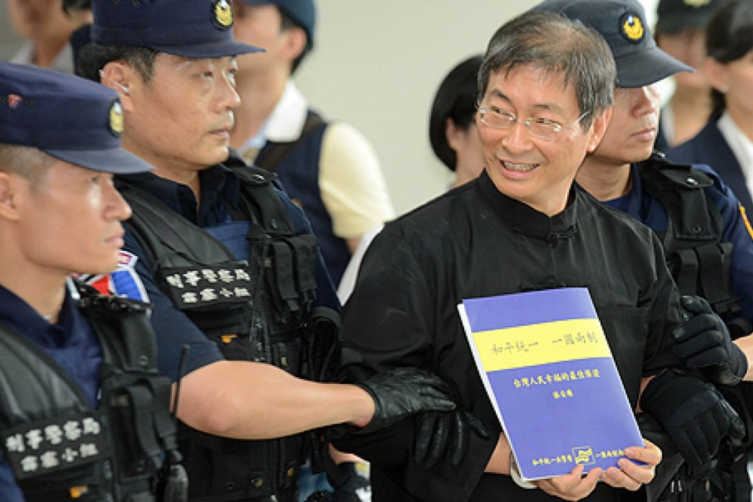 Chang An-lo displays a document that reads "On China Two System" as he is escorted away by police after landing at the Songshan Airport. Photo: AFP
