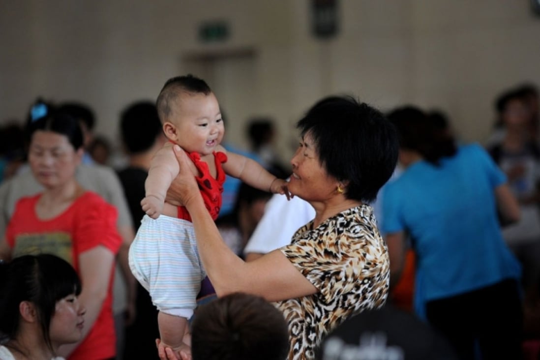 A Chinese granny holding a baby up.