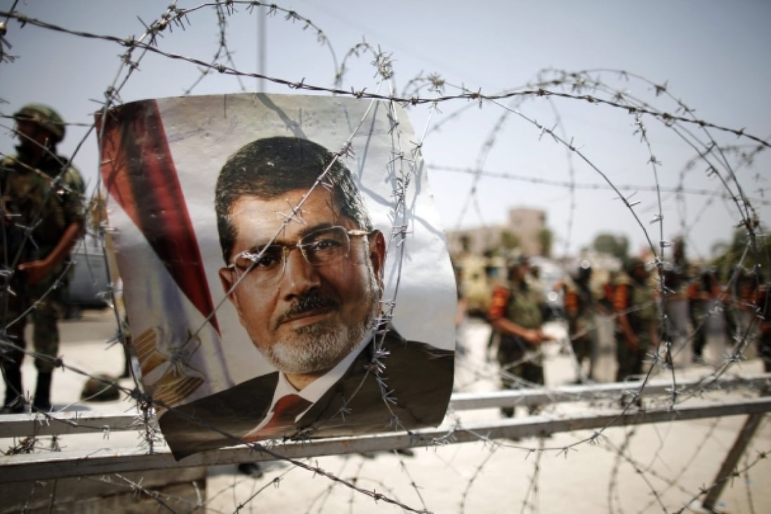 A portrait of deposed Egyptian President Mohamed Mursi is seen on barbed wire outside the Republican Guard headquarters in Cairo. Photo: Reuters