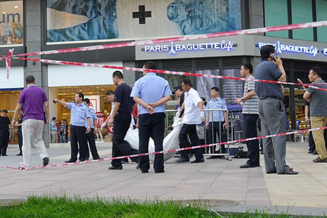 A dead body is carried away after a knife-wielding man killed two people near a shopping mall in Beijing. Photo: AFP