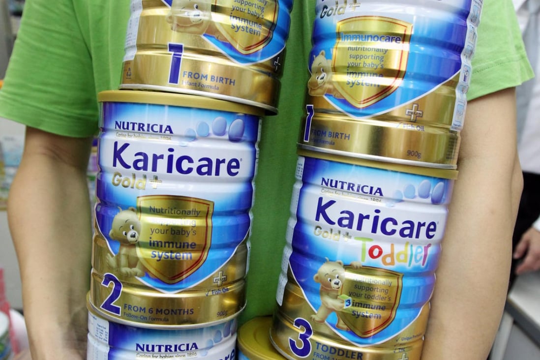 A Wan Chai pharmacy worker removes tins of Karicare infant milk formula, which a distributor recalled as a precaution. Photo: David Wong