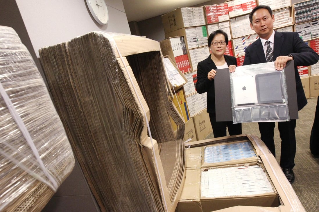 Customs' Lai Sau-ieng (left) and Wan Hing-chuen show seized cigarettes, tablet computers and mobile phones. Photo: David Wong