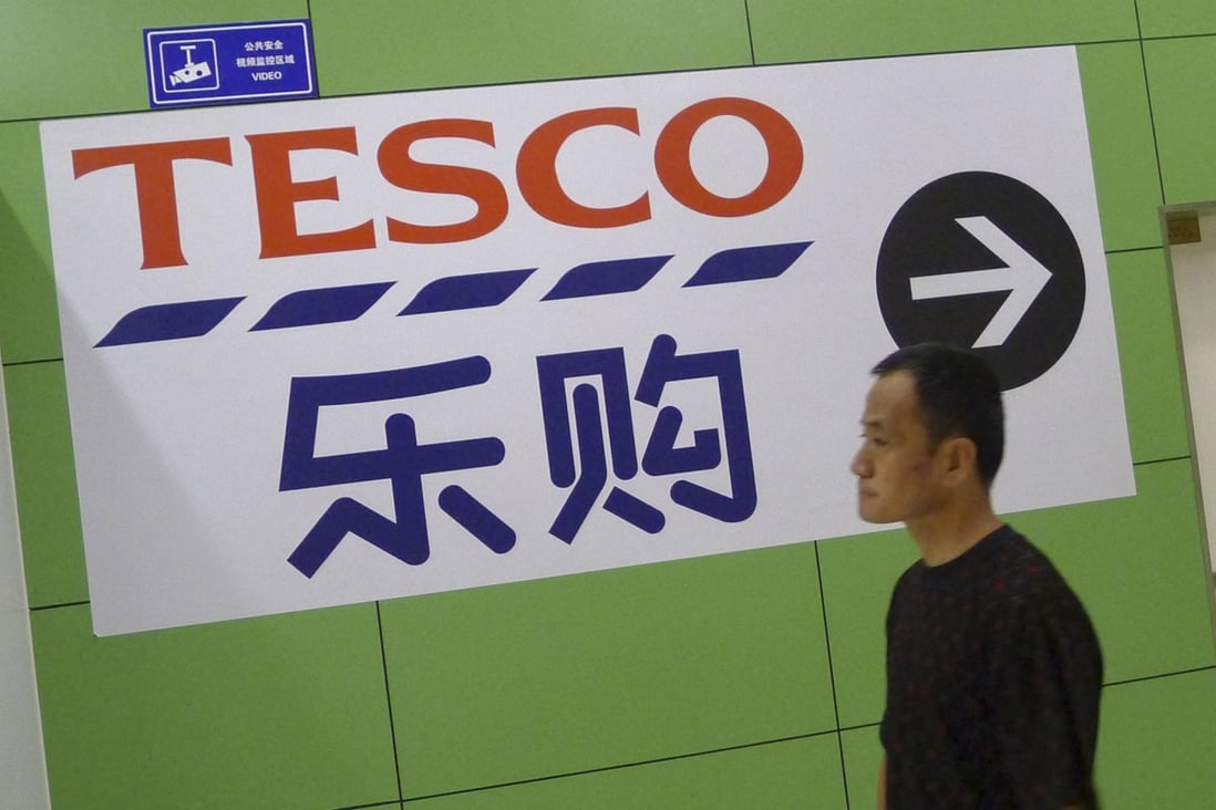 A customer walks past a board showing the direction to a Tesco supermarket in Qingdao. Photo: Reuters