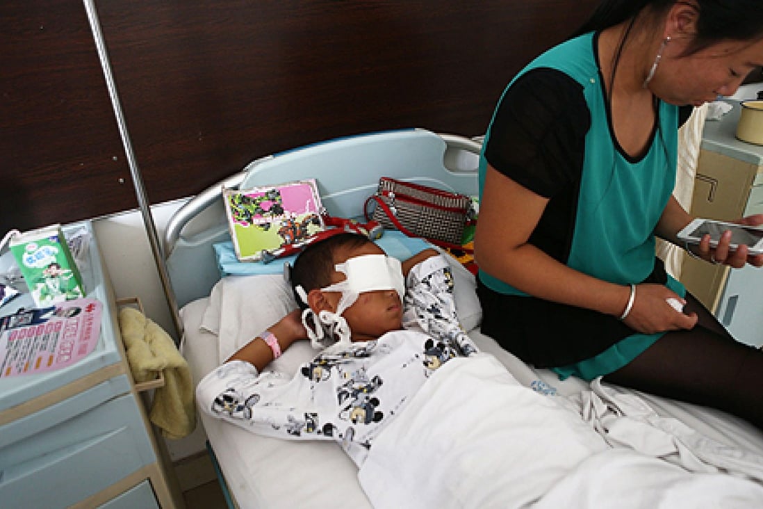 A boy lies on his hospital bed with his eyes covered with bandages as his mother sits next to him in Taiyuan, north China's Shanxi province on Tuesday. Photo: AFP