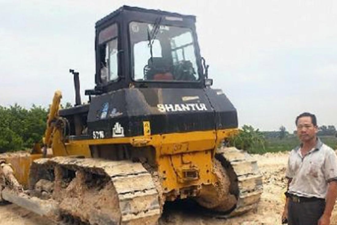 Hong Deliang, a relative of the victim, beside the bulldozer. Photo: SCMP