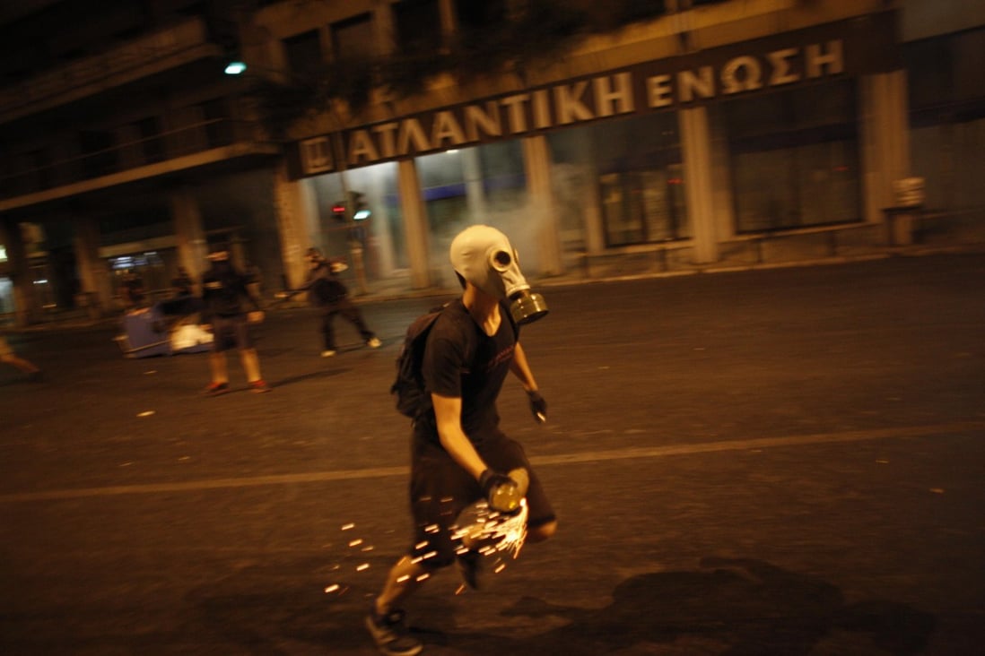 A protester wearing a gas mask hurls a petrol bomb at police during a protest against the far-right Golden Dawn party in Athens.Photo: AP