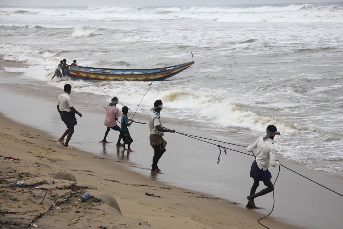 Fishermen pull a boat from the waters of the Bay of Bengal to safer ground at Podampata. Photo: Reuters