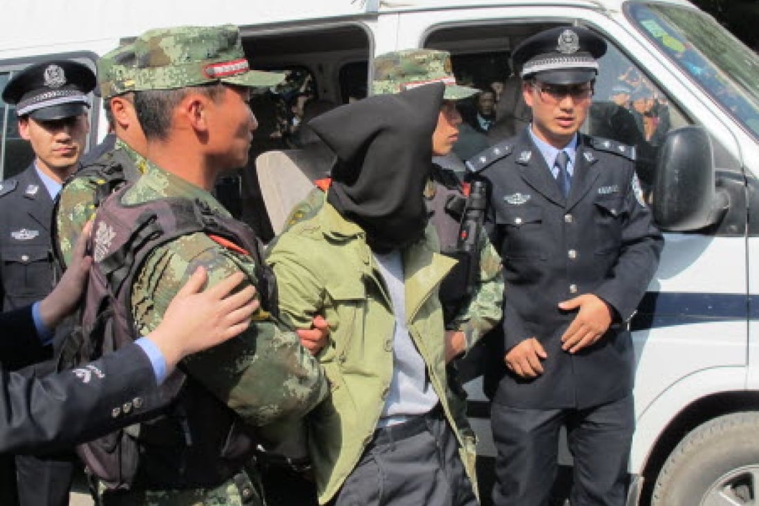 Farmer Ma Yongdong (hooded) is taken to the scene of the crime in Pengyang county after he was arrested in a distant town following the stabbing attack. Photo: Xinhua