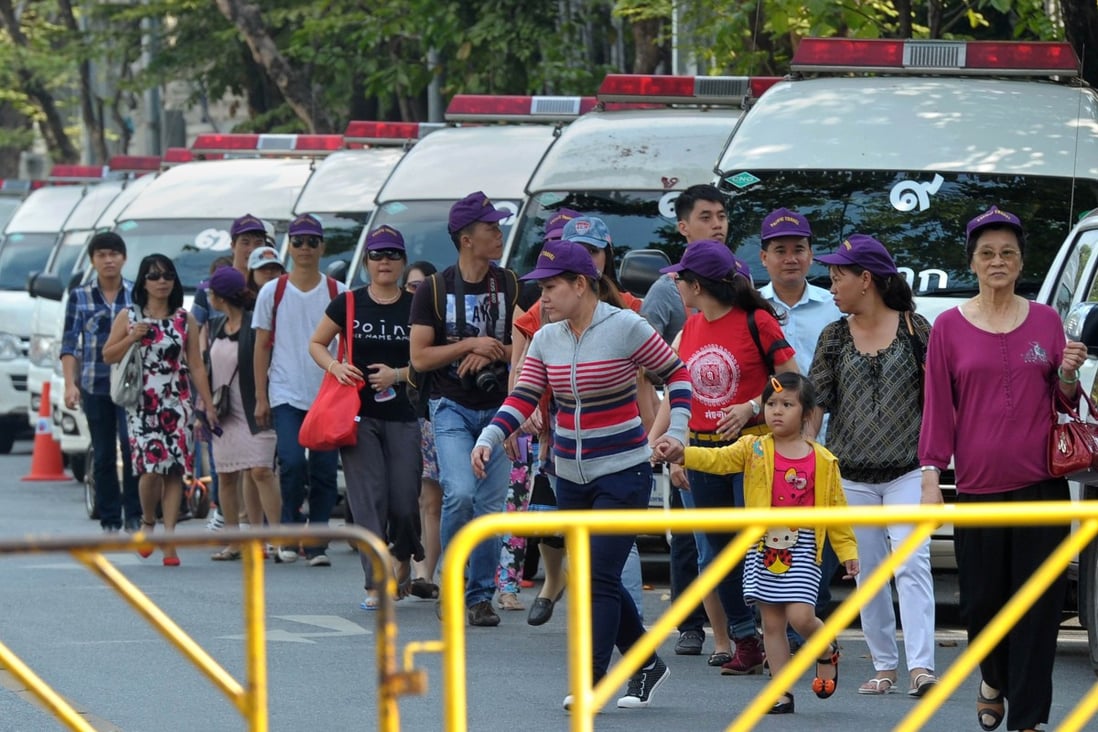 Foreign tourists walk past police vans outside the parliament building in Bangkok on Tuesday. Photo: AFP