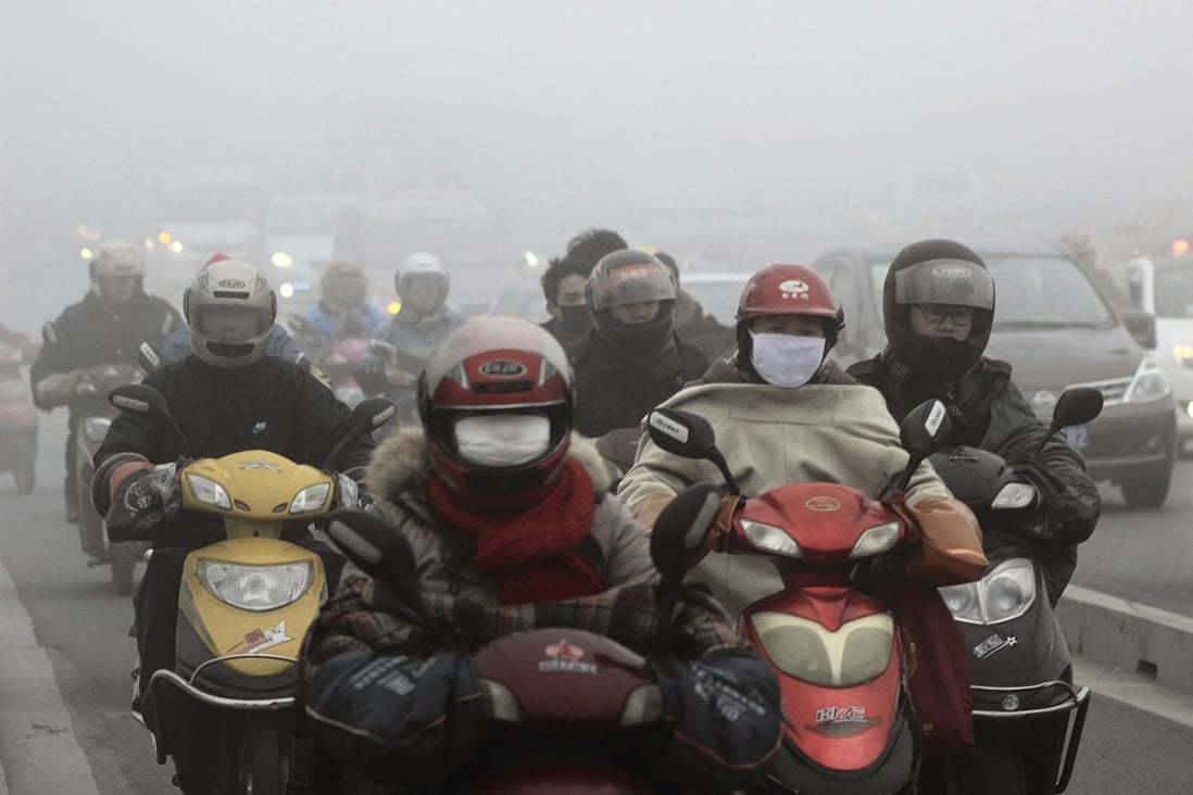 Residents wearing masks ride their electric bicycles on a street amid heavy haze in Shaoxing, Zhejiang province. Photo: Reuters