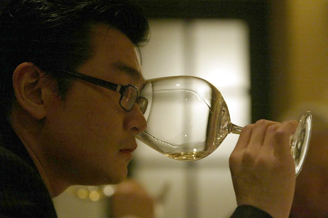 Wine dealer Rudy Kurniawan examines wine at a dinner in March 2005 in Los Angeles, California. He was found guilty in a trial December 18, 2013 in New York  of masterminding a lucrative scheme to sell fake vintage wine in New York and London. Photo: MCT