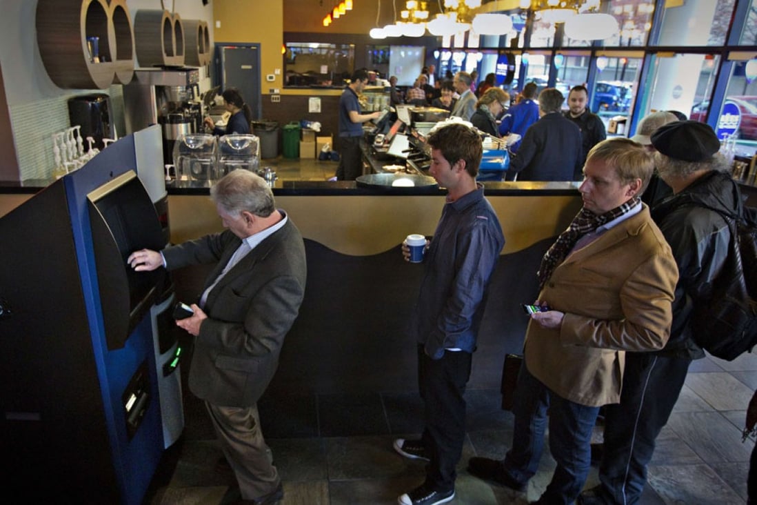 Users queue at a bitcoin ATM in Vancouver. Cash is inserted and a smartphone scan transfers bitcoins to a digital wallet. Photos: Reuters