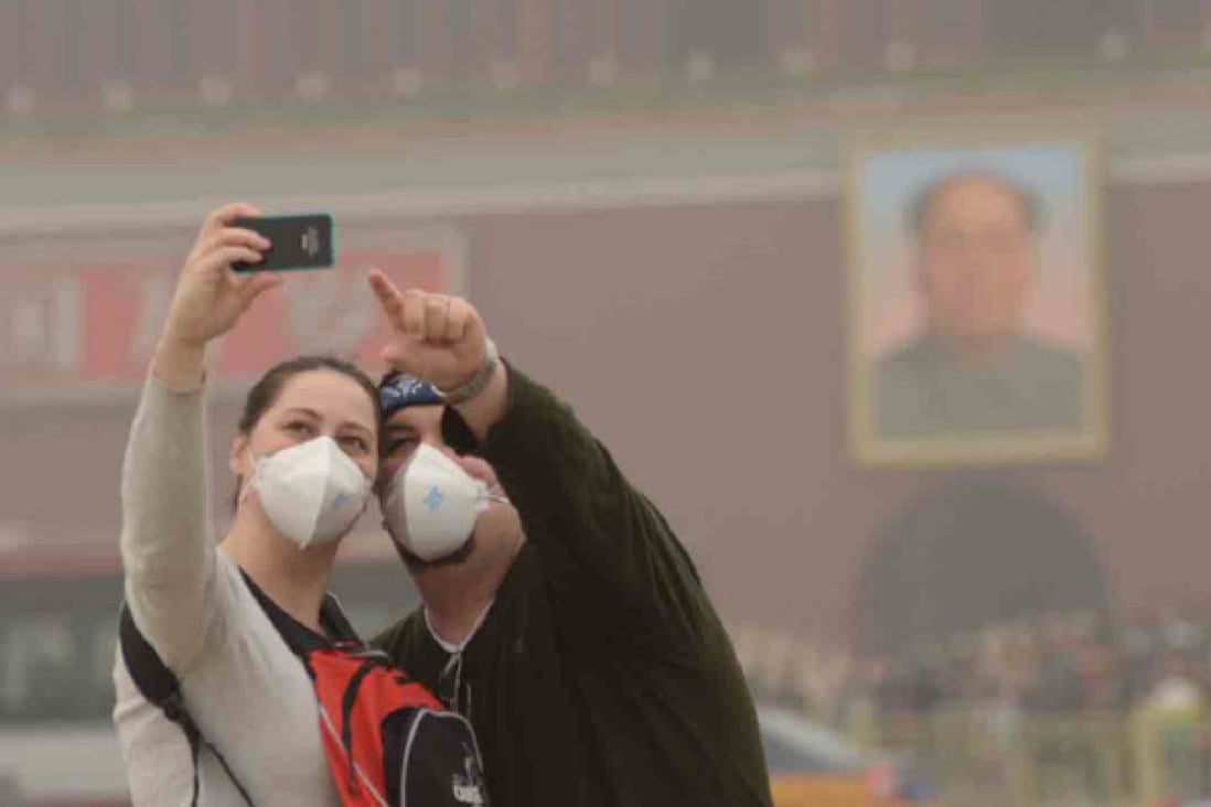 Tourists take a photo of themselves at Tiananmen Square in Beijing on one of many heavily polluted days last year. Photo: China Foto Press