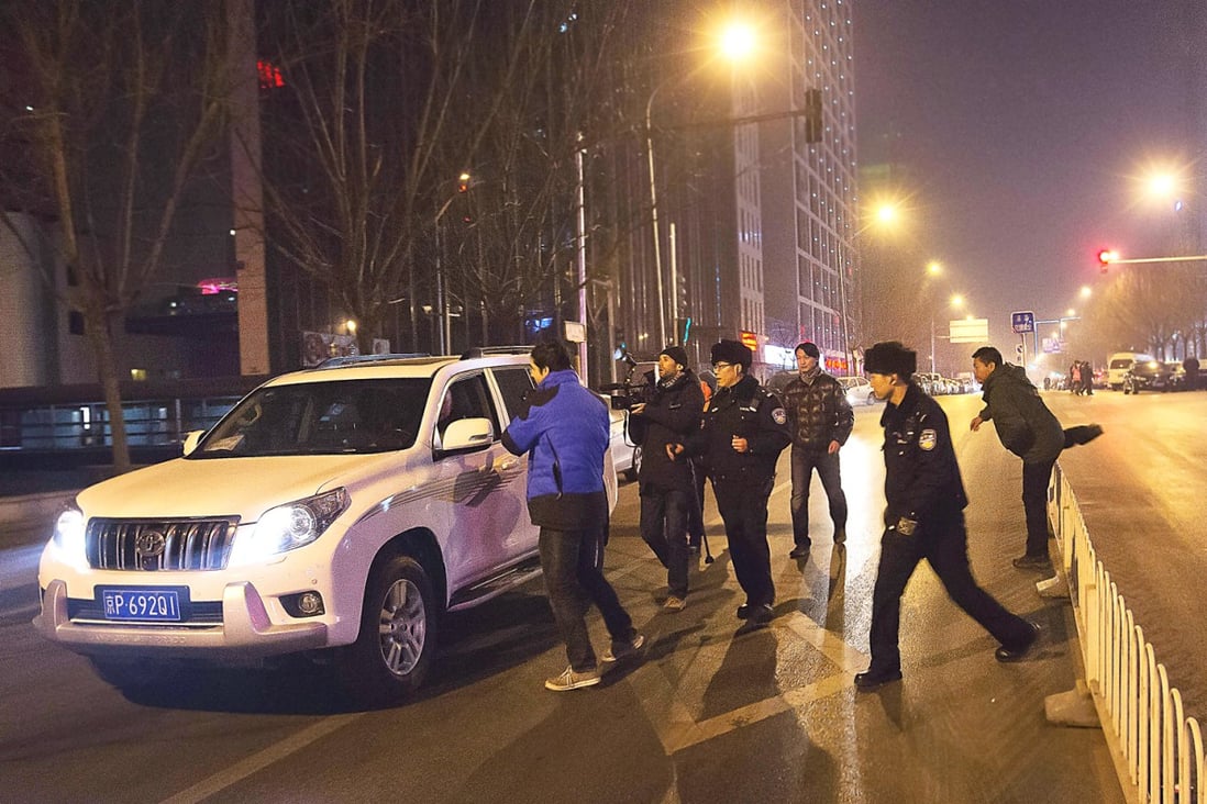 Policemen rush to prevent journalists to interview Zhang Qingfang, the lawyer of Xu Zhiyong, near the No. 1 Intermediate People's Court, where Xu stood trial, in Beijing Wednesday. Photo: AP