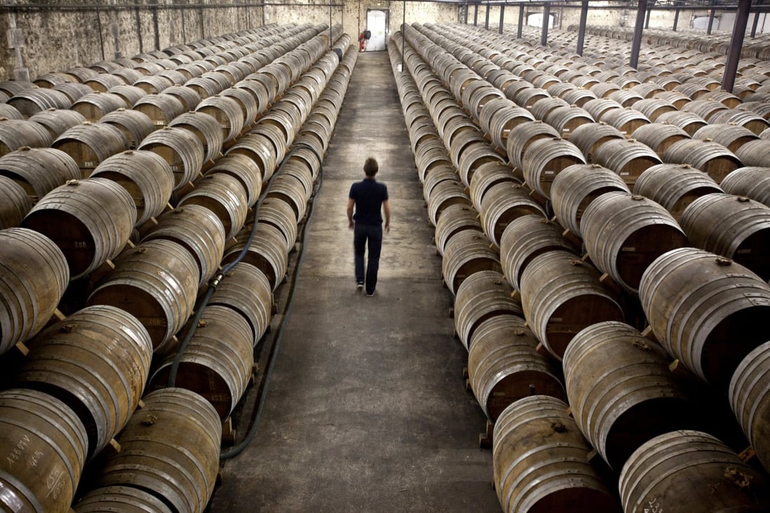 An employee walks between barrels of Remy Martin Fine Champagne Cognac, laid to age in a cellar at the Remy Cointreau SA headquarters in Cognac, France.