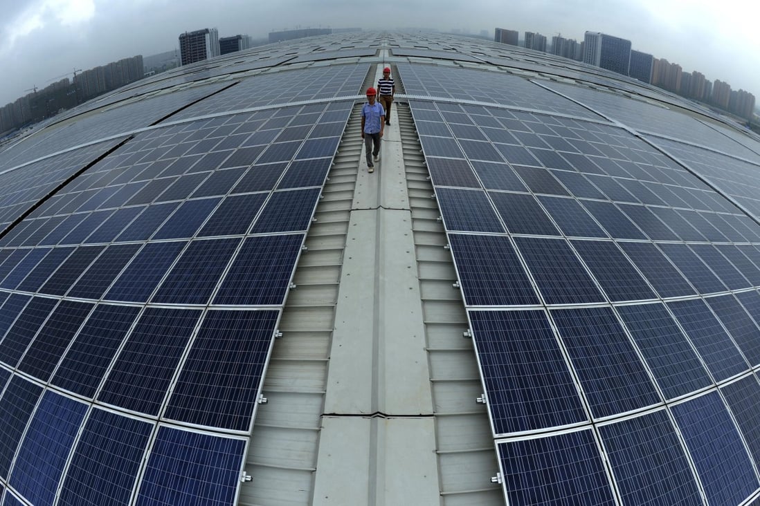 Workers walk between solar panels on the roof of Hangzhou East railway station in Zhejiang province. Photo: AP
